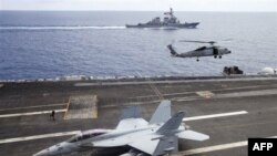 Máy bay chiến đấu F/A-18F Super Hornet và trực thăng SH-60 Seahawk của hải quân Mỹ trên tàu sân bay USS George Washington, phía sau là tàu khu trục USS John S. McCain (DDG-56) ngoài khơi bờ biển Việt Nam, ngày 13/8/2011